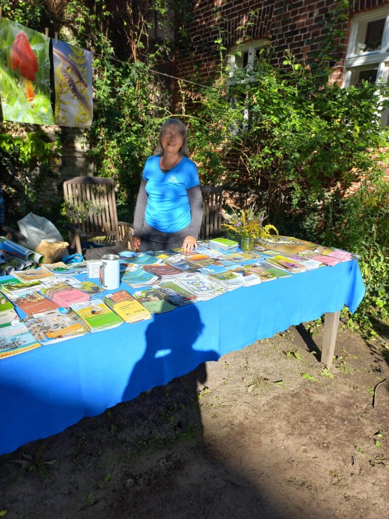 Eine Frau steht am NABU-Infostand. Auf dem Tisch sind zahlreiche Broschüren, Flyer und andere Veröffentlichungen ausgelegt.